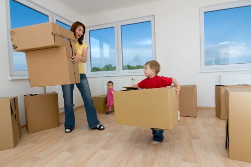 Professional movers carrying furniture through a flat hallway in Perivale